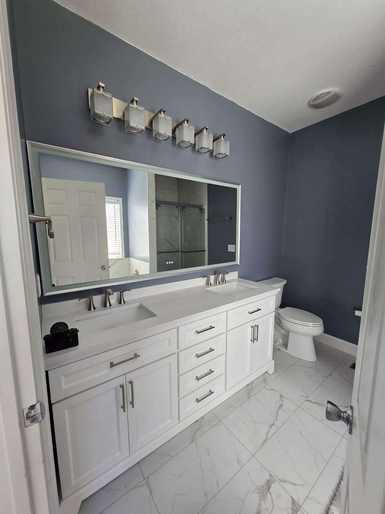 White double vanity, LED mirror, marble-look floor